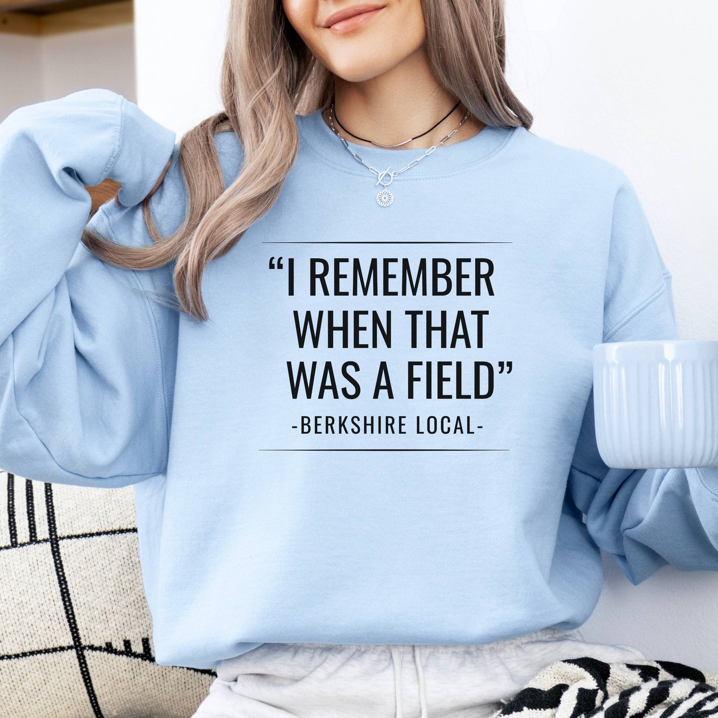 Person wearing sweatshirt with the quote "I remember when that was a field" -Berkshire Local-, in the color light blue