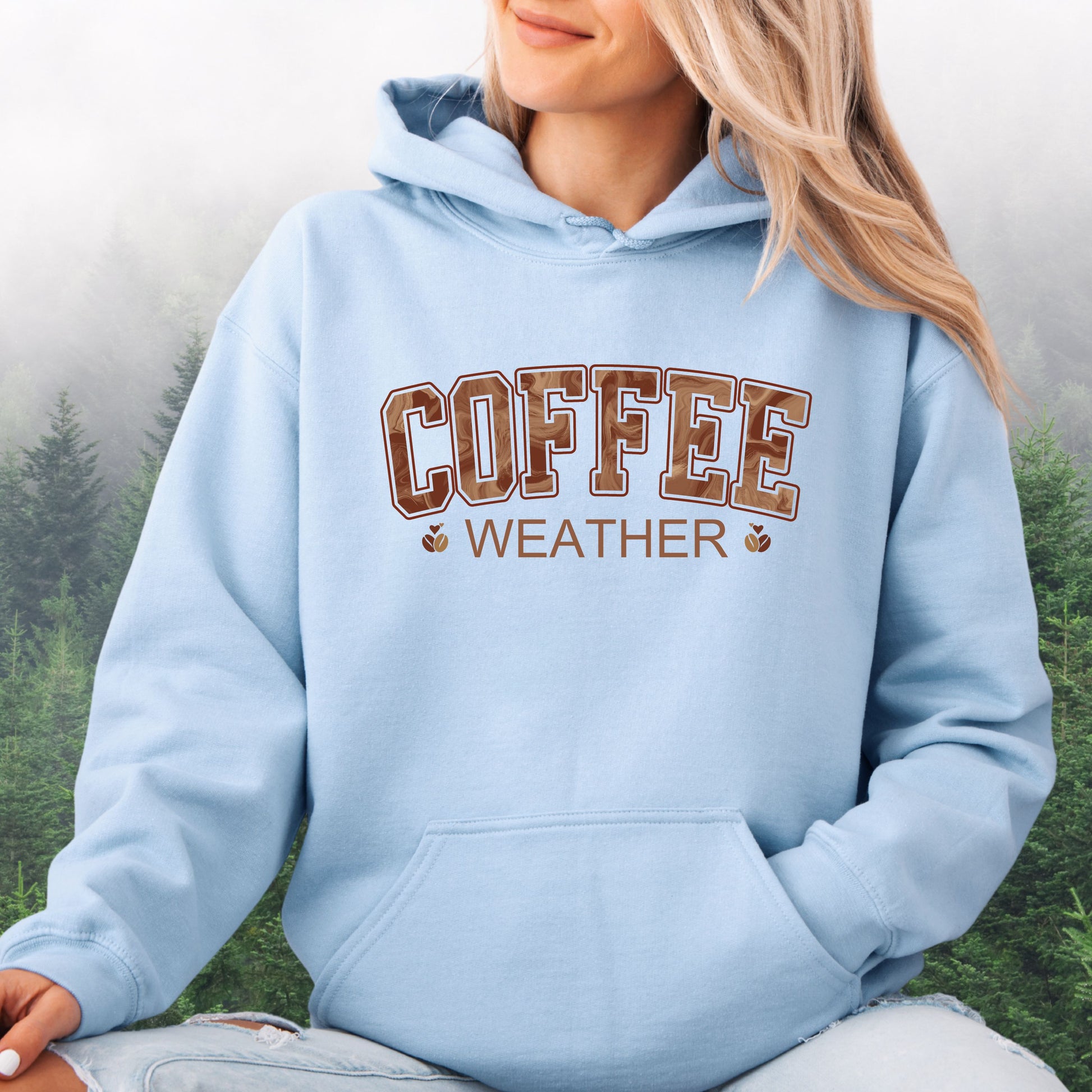 Person wearing light blue coffee weather hoodie with marbled brown lettering and coffee bean icons.
