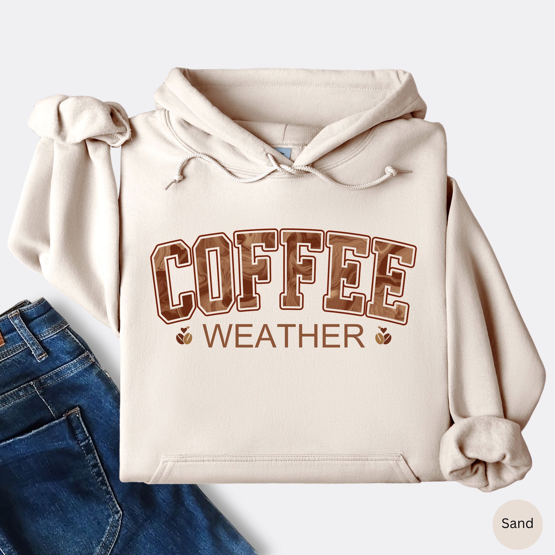 Sand colored coffee weather hoodie with marbled brown lettering and coffee bean icons.