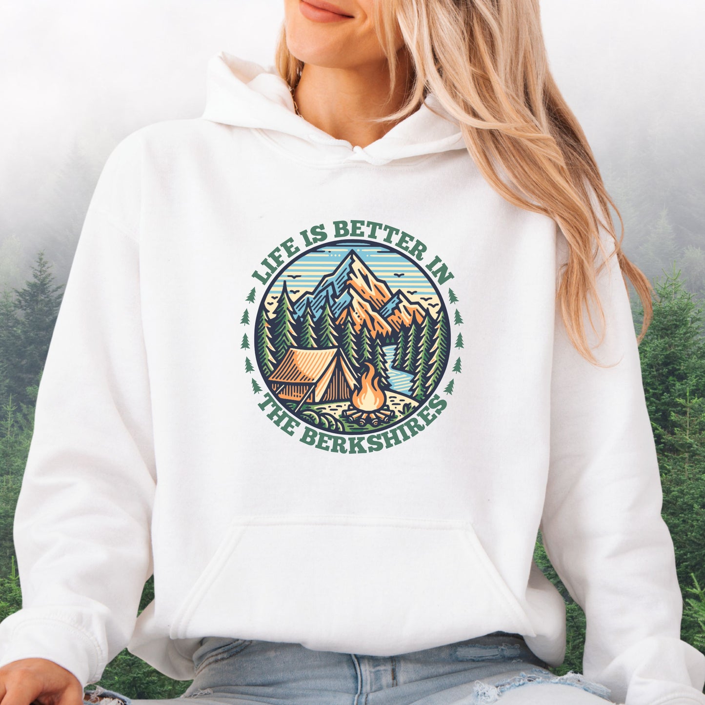 Person wearing white hoodie with mountain scene, pine trees, tent, and campfire graphic with the text Life is Better in the Berkshires