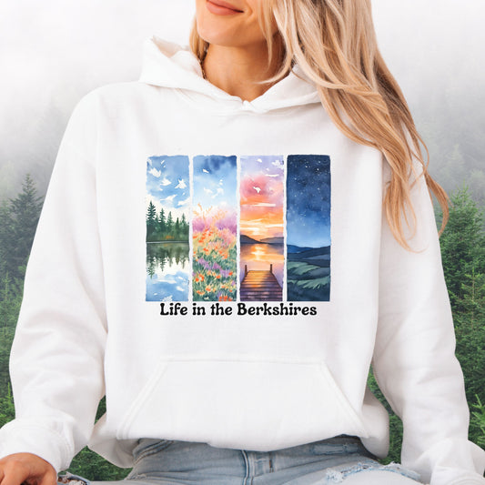 Model wearing the white Life in the Berkshires hoodie with scenic landscape panel design on the front