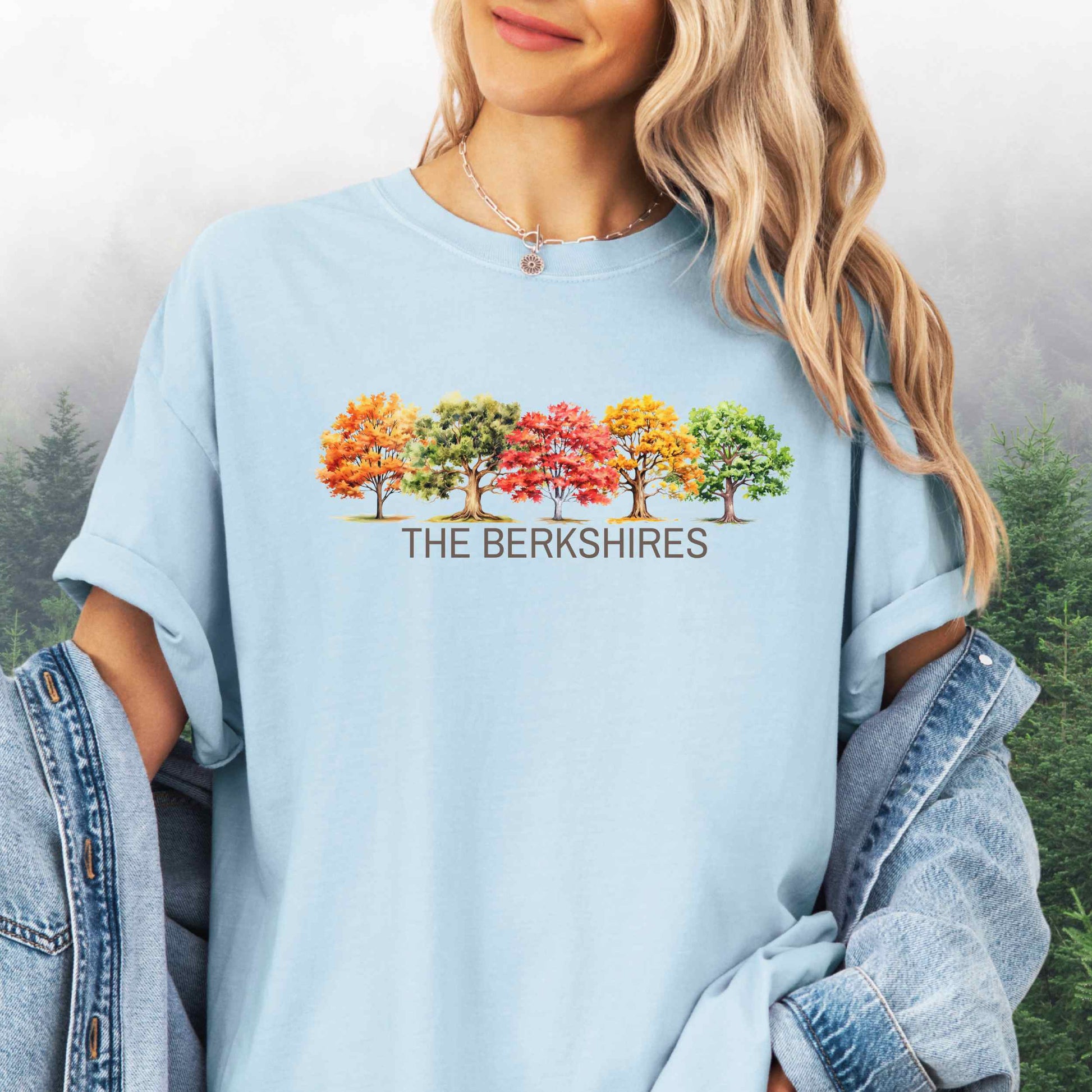 Person wearing The Berkshires Fall t-shirt with autumn trees in the color chambray.