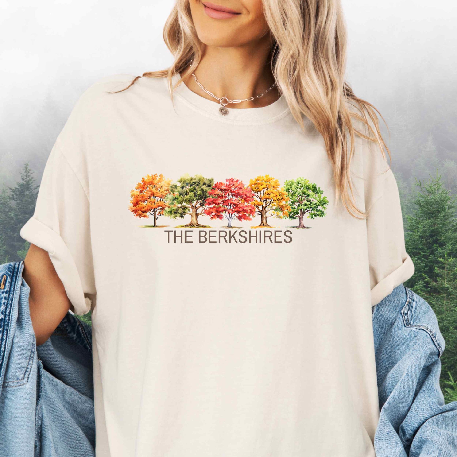 Person wearing The Berkshires Fall t-shirt with autumn trees in the color ivory.