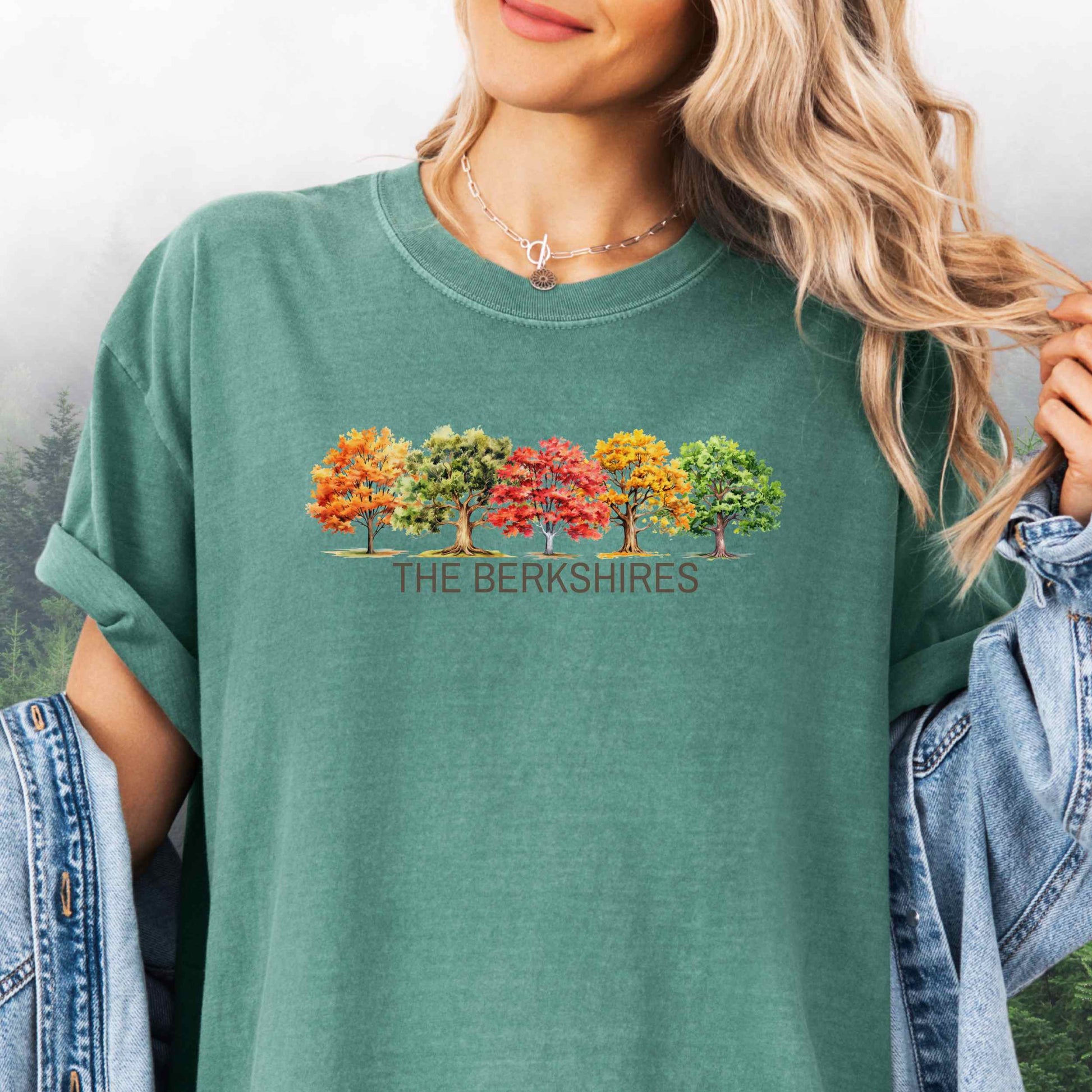Person wearing The Berkshires Fall t-shirt with autumn trees in the color light green.
