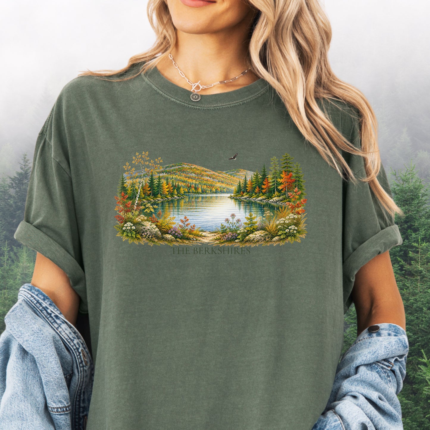 Person wearing The Berkshires autumn landscape Comfort Colors T-shirt with colorful fall foliage, mountains, lake and eagle in the color Moss.
