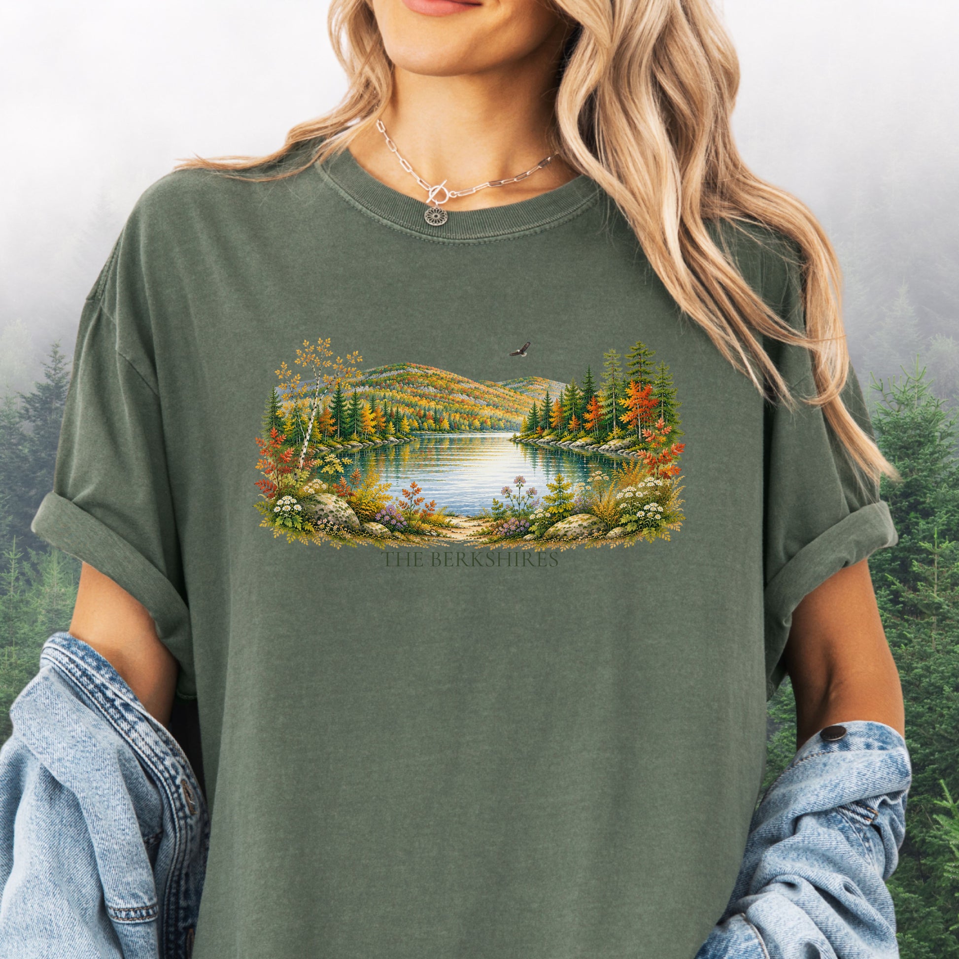 Person wearing The Berkshires autumn landscape Comfort Colors T-shirt with colorful fall foliage, mountains, lake and eagle in the color Moss.
