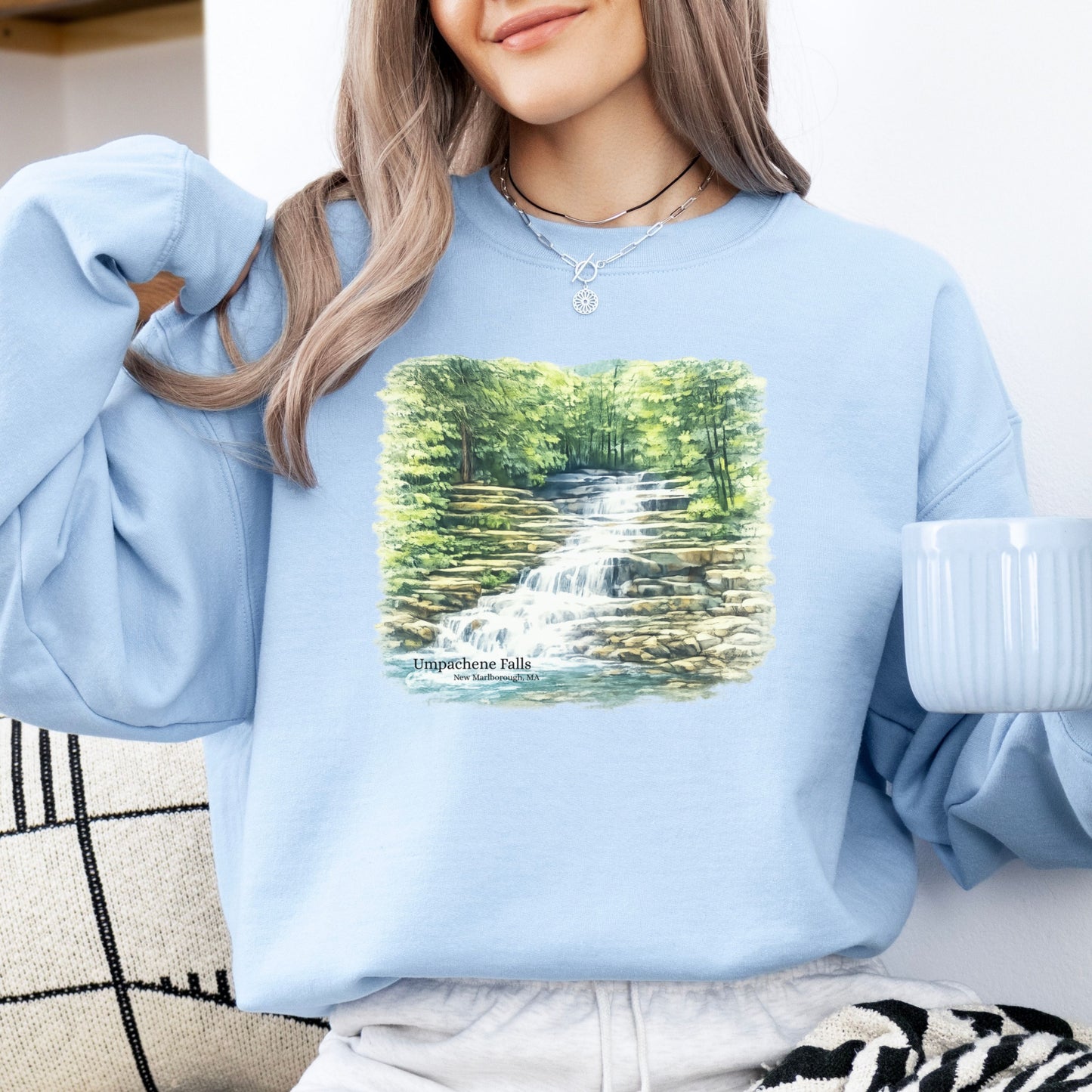 Person wearing Umpachene Falls crewneck sweatshirt with waterfall design in the color light blue