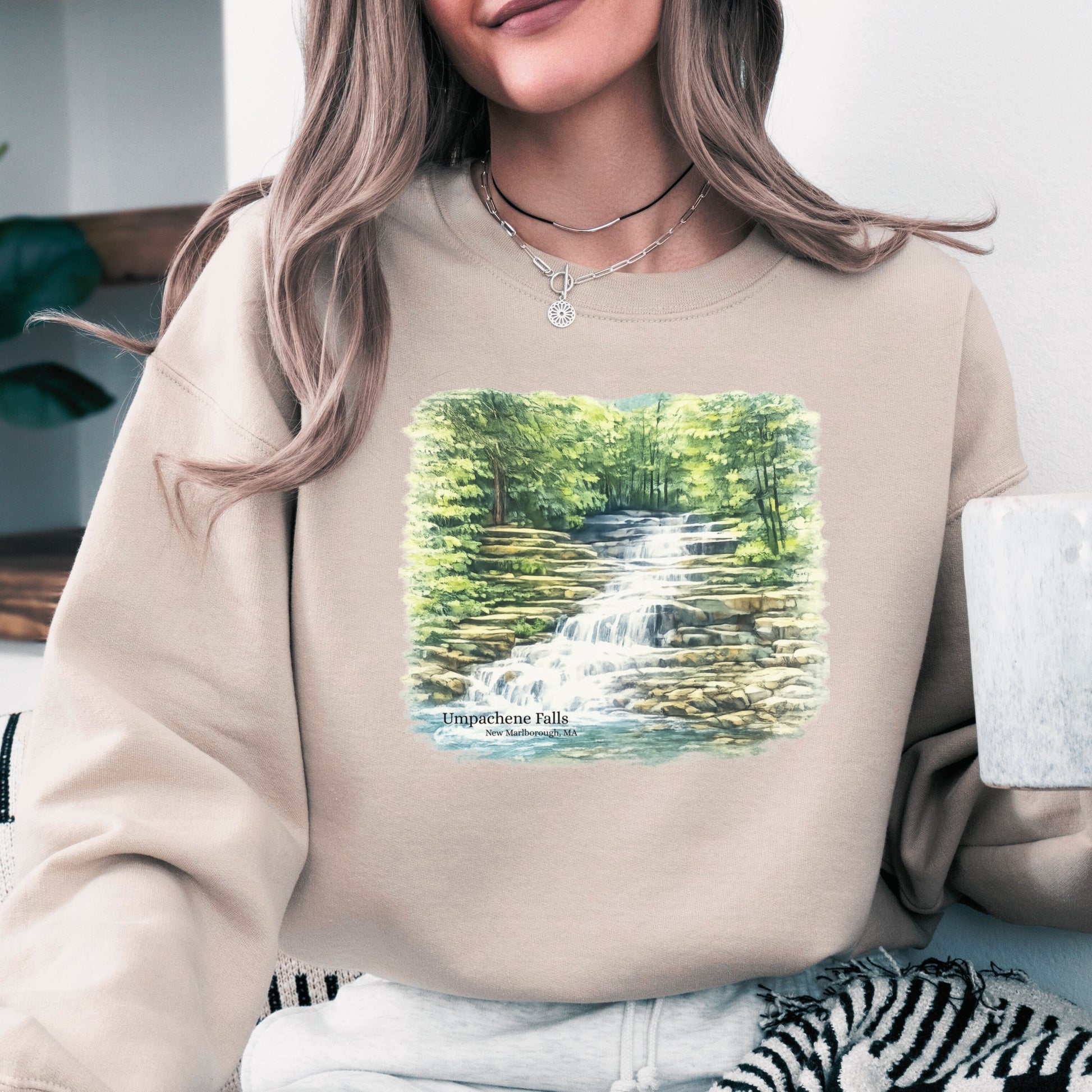 Person wearing Umpachene Falls crewneck sweatshirt with waterfall design in the color sand