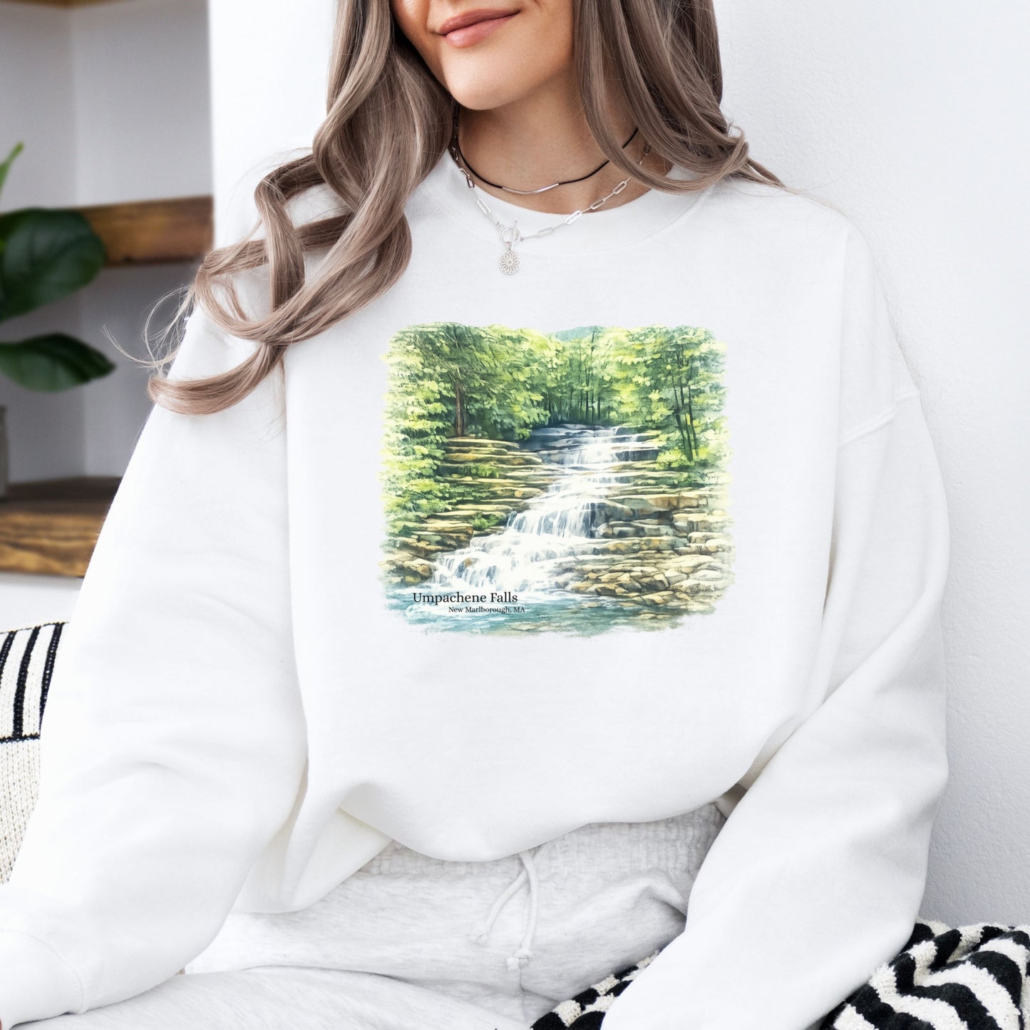 Person wearing white Umpachene Falls crewneck sweatshirt with waterfall design