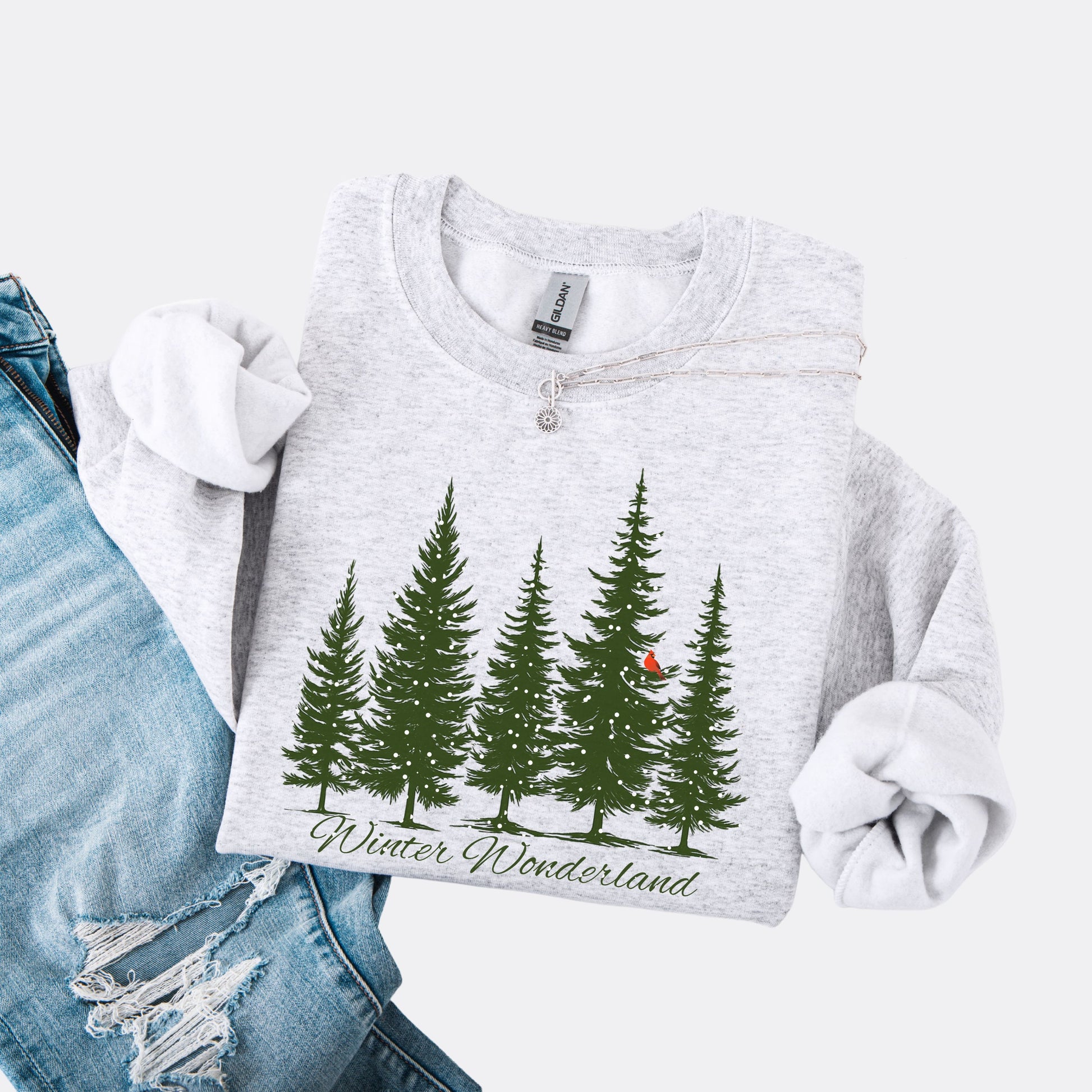 Snow covered evergreen trees with red cardinal design on ash colored sweatshirt with Winter Wonderland text