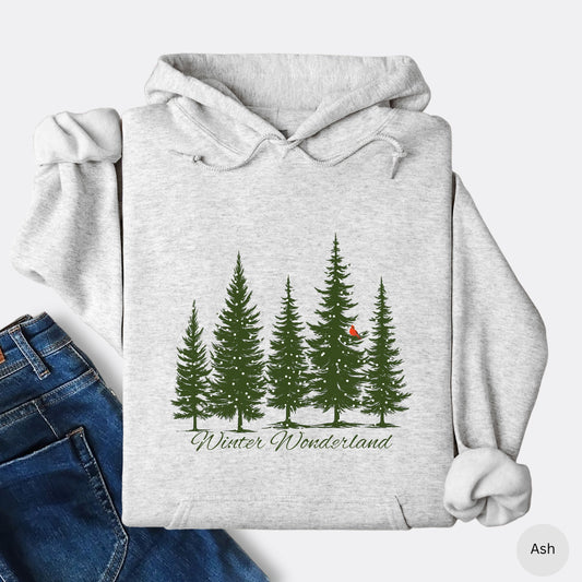 Snowy pine trees and red cardinal design on cozy unisex winter hoodie in the color ash