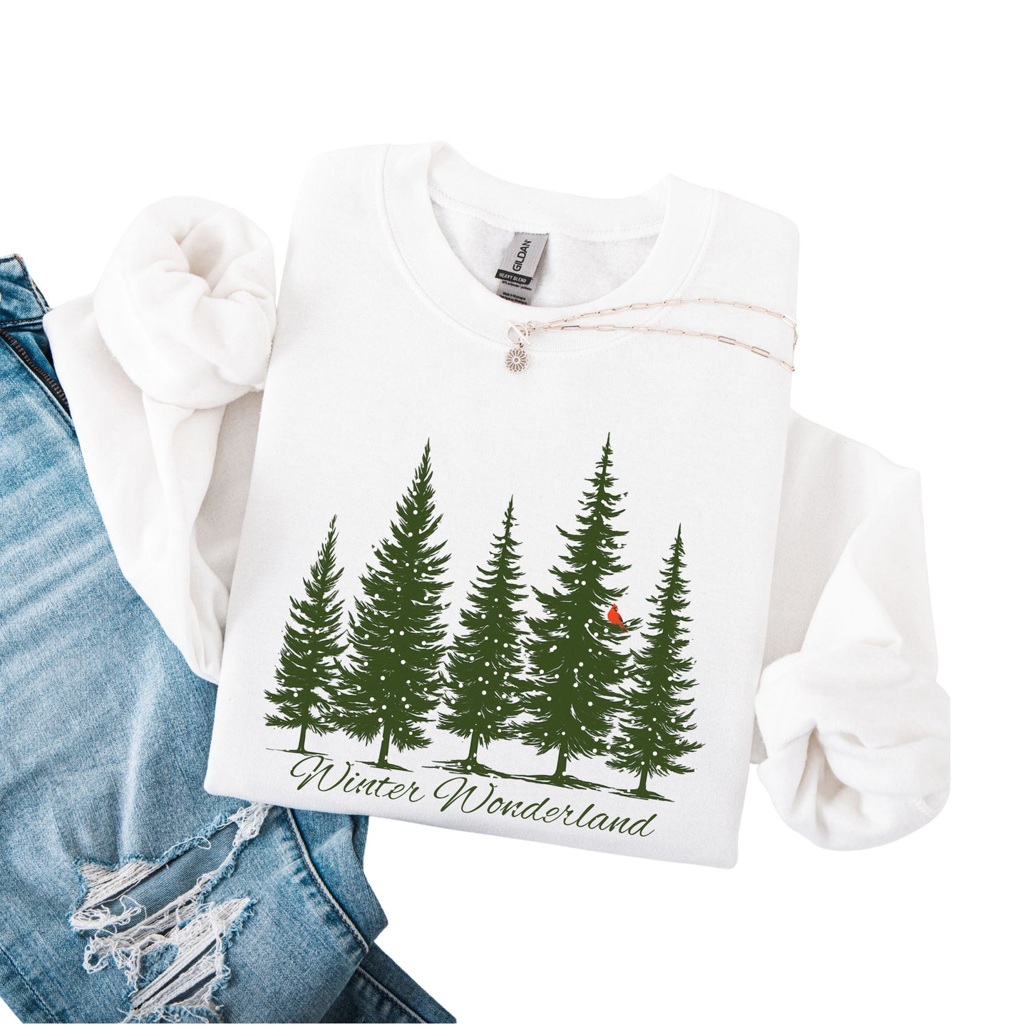 Snow covered evergreen trees with red cardinal design on white sweatshirt with Winter Wonderland text