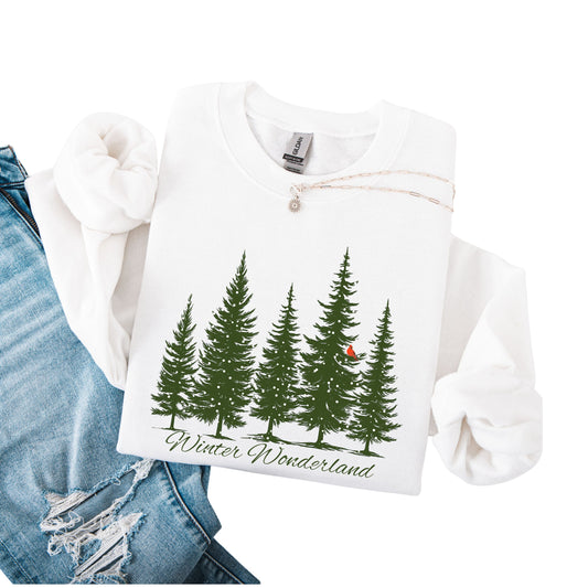 Snow covered evergreen trees with red cardinal design on white sweatshirt with Winter Wonderland text