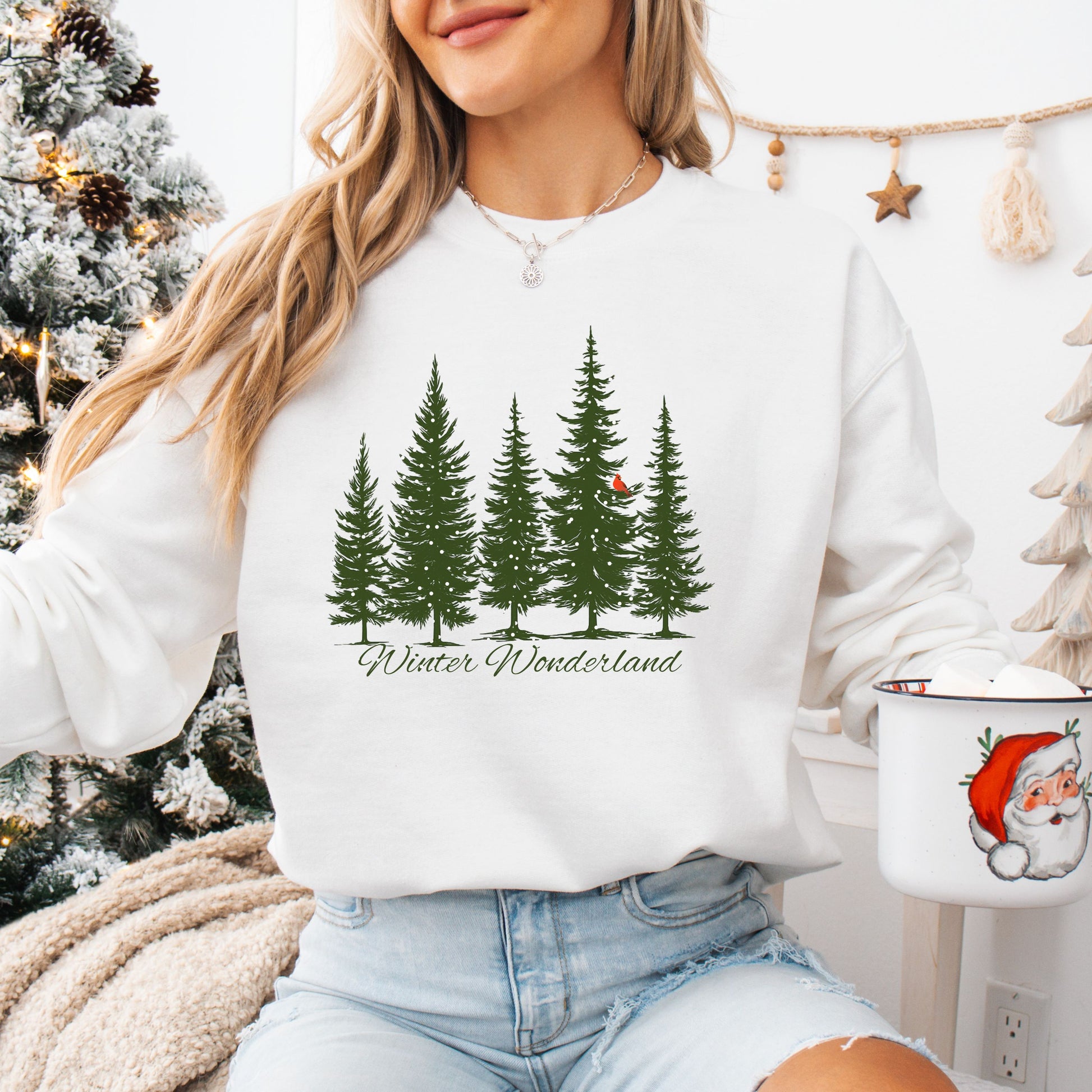 Person wearing snow covered evergreen trees with red cardinal design on white sweatshirt with Winter Wonderland text