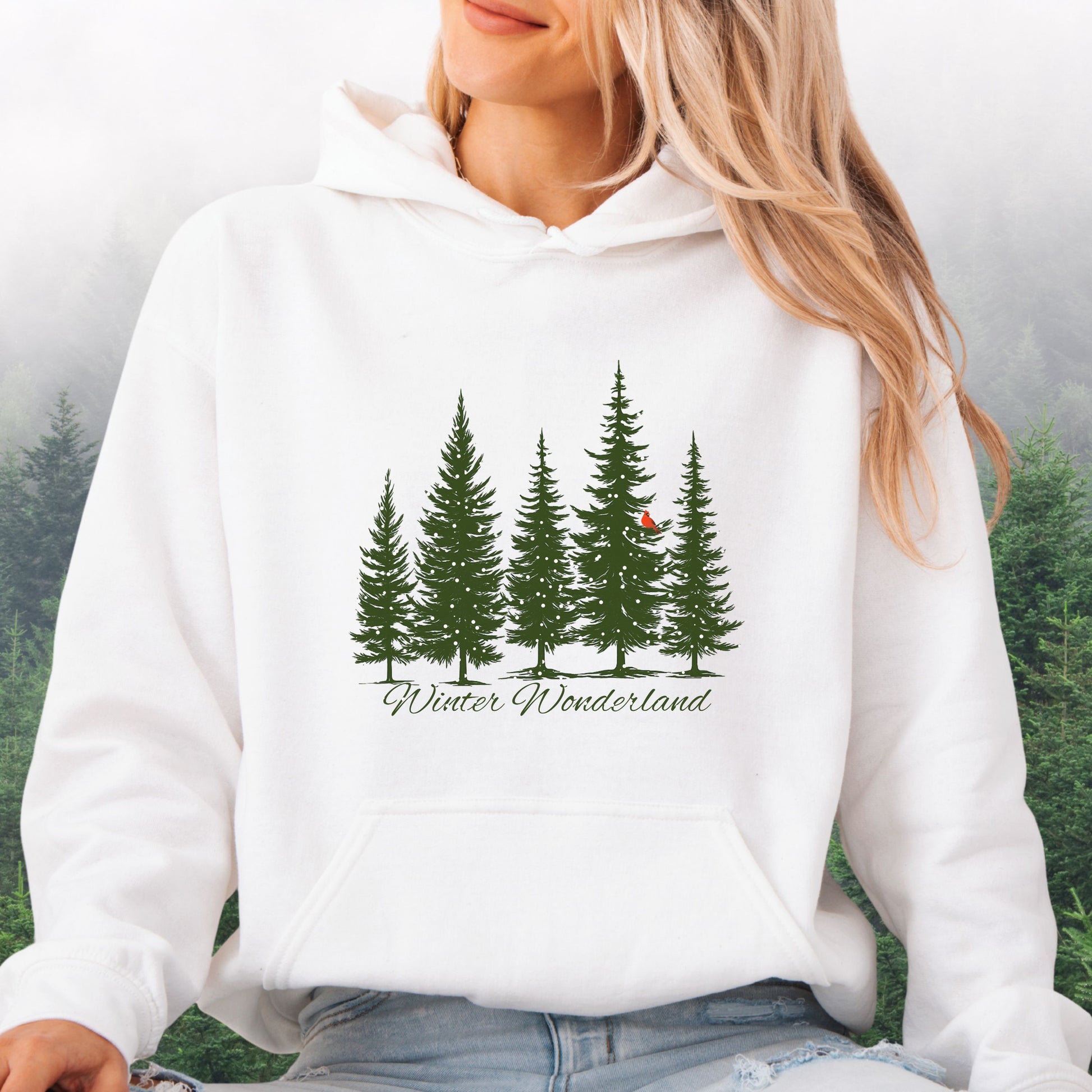 Person wearing snowy pine trees and red cardinal design on cozy unisex winter hoodie in the color white